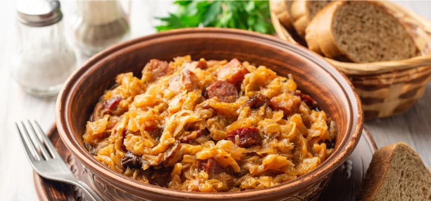 A bowl of bigos, Poland's hunter's stew of sauerkraut, fresh cabbage, pork, and smoked sausage, served with rye bread.