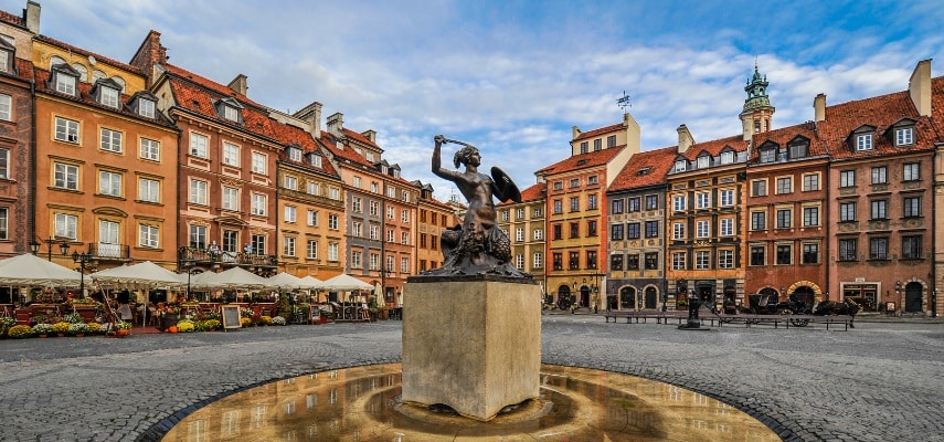 Colorful townhouses around Warsaw's Old Town Market Square with the Mermaid statue in the center.